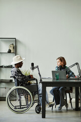 Vertical full length portrait of African-American person with disability speaking to microphone...