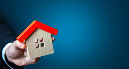 Hand with a house on a blue background. Buying and selling housing. Search for options. Buy, rent....