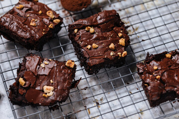 Chocolate brownies with hazelnut crumbs on top, on a tray with cacao powder, chocolate crumbs on a white rustic background. Very fudge brownies