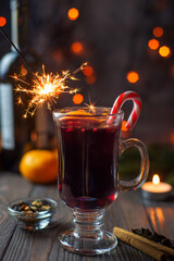 Mulled wine in a glass with sparklers and spices on a bokeh background