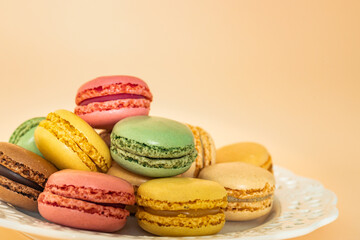 French macaroons on an apricot background. Delicious colorful almond cookies, dessert. 