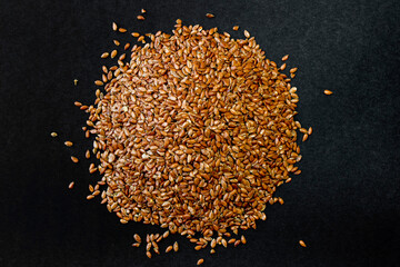 Flax grains on a black background. Healthy seeds. A handful of seeds. - obrazy, fototapety, plakaty
