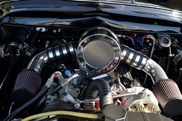 Fototapeta na wymiar AUTOMOTIVE: Under the hood view of a Dual Carb Engine with shiny parts and fluted filters.