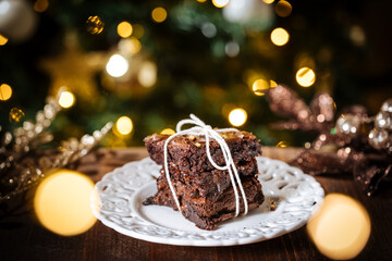 Fototapeta na wymiar Chocolate brownies wrapped in group as a present in front of Christmas tree with Christmas lights in festive atmosphere and decoration