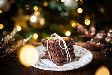 Chocolate brownies wrapped in group as a present in front of Christmas tree with Christmas lights...