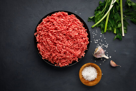 Minced meat, spices and herbs on black background. Top view.