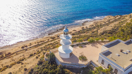 Faro del Cabo de las Huertas en Alicante , vista aérea en un día luminoso y con el mar peinado por el fuerte viento de poniente y con un fuerte color azul del mar.