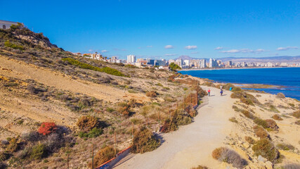 Fototapeta na wymiar Faro del Cabo de las Huertas en Alicante , vista aérea en un día luminoso y con el mar peinado por el fuerte viento de poniente y con un fuerte color azul del mar.