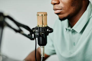 Close up of African-American man speaking to microphone while recording podcast at home