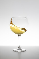 White wine swirling in glass on white background