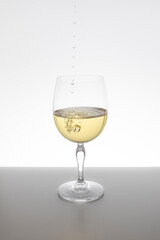 white wine falling in glass on white background