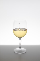 white wine falling in glass on white background