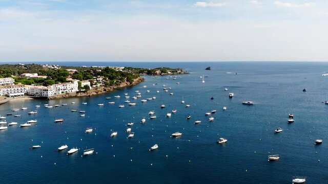 Drone shot of the coastal city of Cadaques. Small village on the Costa Brava. View from the drone of the beach and the bay in Spain. Boats in a rocky bay in Cadaques. Churches in Cadaques. 