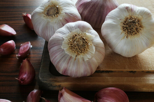 Garlic bulbs on the cutting board with garlic cloves on the rustic table. Seletive focus.