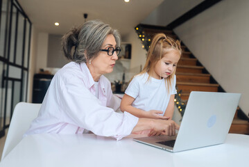 Child and granny looking at the camera with laptop