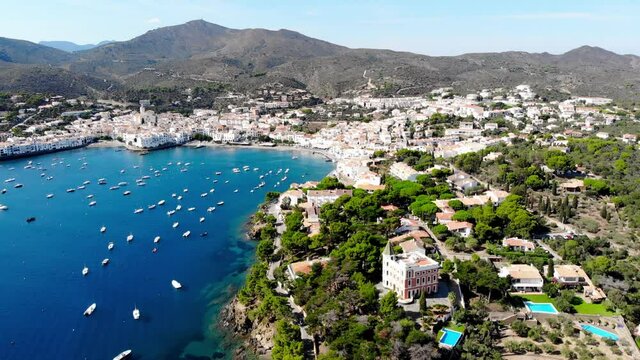 Drone shot of the coastal city of Cadaques. Small village on the Costa Brava. View from the drone of the beach and the bay in Spain. Boats in a rocky bay in Cadaques. Churches in Cadaques. 