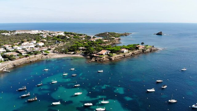 Drone shot of the coastal city of Cadaques. Small village on the Costa Brava. View from the drone of the beach and the bay in Spain. Boats in a rocky bay in Cadaques. Churches in Cadaques. 