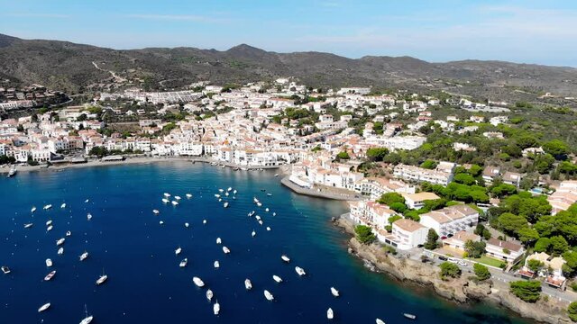 Drone shot of the coastal city of Cadaques. Small village on the Costa Brava. View from the drone of the beach and the bay in Spain. Boats in a rocky bay in Cadaques. Churches in Cadaques. 