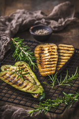 Grilled zucchini and eggplant slices on a cooling rack on wooden background, vertical