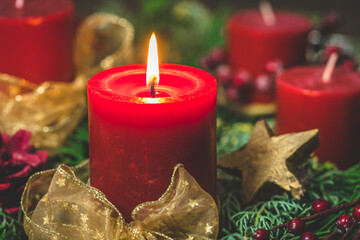 Burning red candle in an advent arrangement with fresh fir branches, first advent