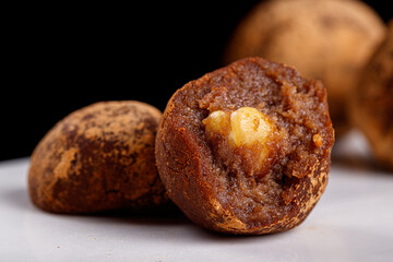 Beautiful candy truffle with a nut inside on a white plate on a black background