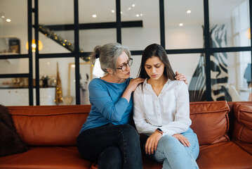 Grandmother comforting her sad granddaughter at home.