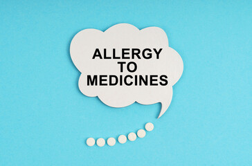 On a blue table are pills and a white plate with the inscription - allergy to medicines