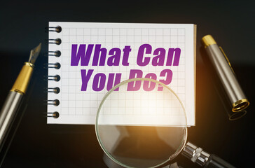 On the black surface is a pen, a magnifying glass and a notebook with the inscription - What Can...