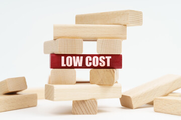 On the white surface there is a ruined tower made of planks, on a red plaque there is an inscription - Low Cost