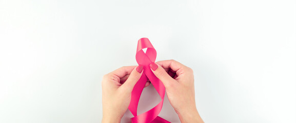 Pink ribbon background. Health care symbol pink ribbon in woman hands on white background. Breast cancer support concept. World cancer day.