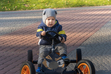 little boy rides a car-bike in the rays of the autumn sun