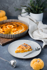 An appetizing piece of fresh sweet layered pumpkin pie in powdered sugar on a plate on the table. Thanksgiving treat. Vertical view
