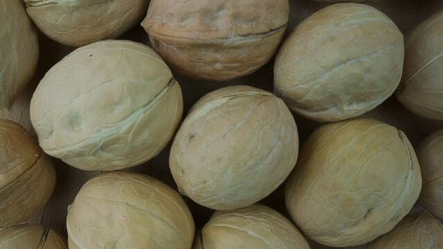 Lot of shelled walnuts rotate on wooden background top view. Nuts crop and harvesting concept.