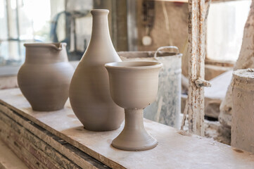 Fototapeta na wymiar a row of freshly made clay cup, vase and a jug at a pottery