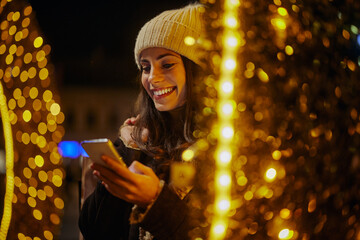 Smiling woman using phone outdoors in decorated city