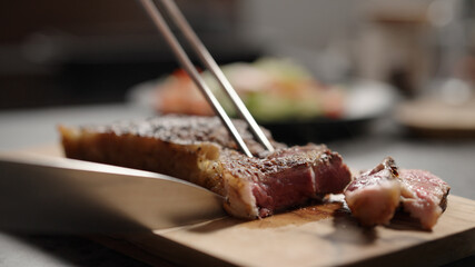 man slicing new york steak on olive wood board