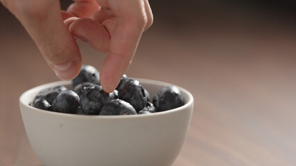fresh washed blueberries picked by man hand from white bowl