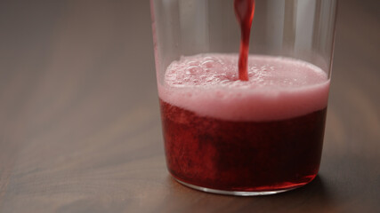 pour cherry drink in tumbler glass closeup