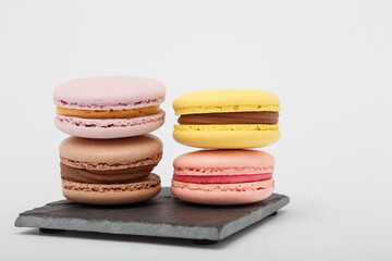 Colorful macaroons on grey mat on white background. Sweet bakery, copy space.