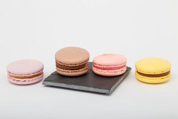 Colorful macaroons on grey mat on white background. Sweet bakery, copy space.