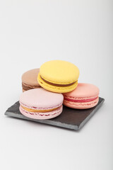 Colorful macaroons on grey mat on white background. Sweet bakery, copy space.