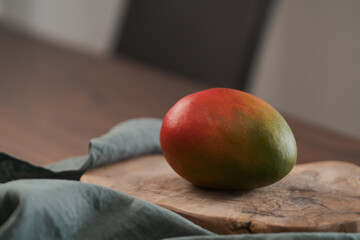 Whole ripe red mango on olive wood board