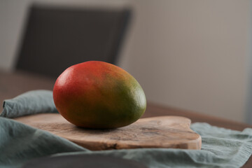 Whole ripe red mango on olive wood board