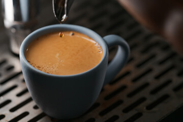 Closeup espresso last drop with single spout portafilter in blue cup