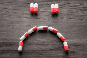 Drug benefits and side effects concept. Close up on a series of pills forming a smile and a sad face. - obrazy, fototapety, plakaty