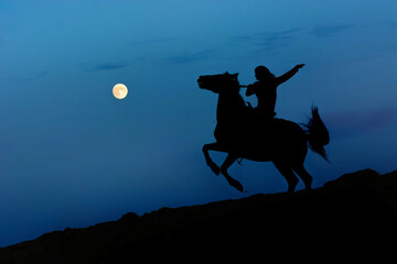 Fantasy full moon with dark silhouette of the horse rearing up on hind legs. Horseback riding, woman rider under moonlight. 