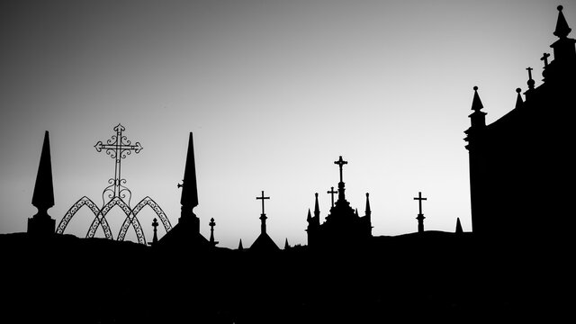Silhouettes of crosses in a twilight cemetery. Black and white photo.