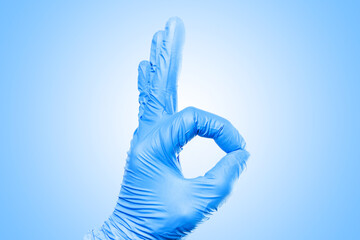 Hand in blue latex glove isolated on white. Showing OK sign. Medical approval background. Fingers connected in zero shape.
