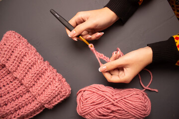 girl's desk for knitting winter clothes from pink yarn with gold crochet