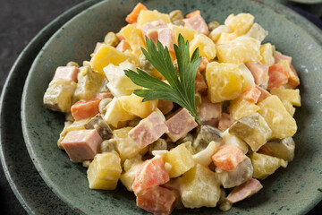 Russian salad Olivier from boiled vegetables and sausage with mayonnaise on black table. close up